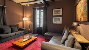 Un soggiorno moderno con un tavolino in vetro, due divani, una moquette rossa e opere d'arte alle pareti.