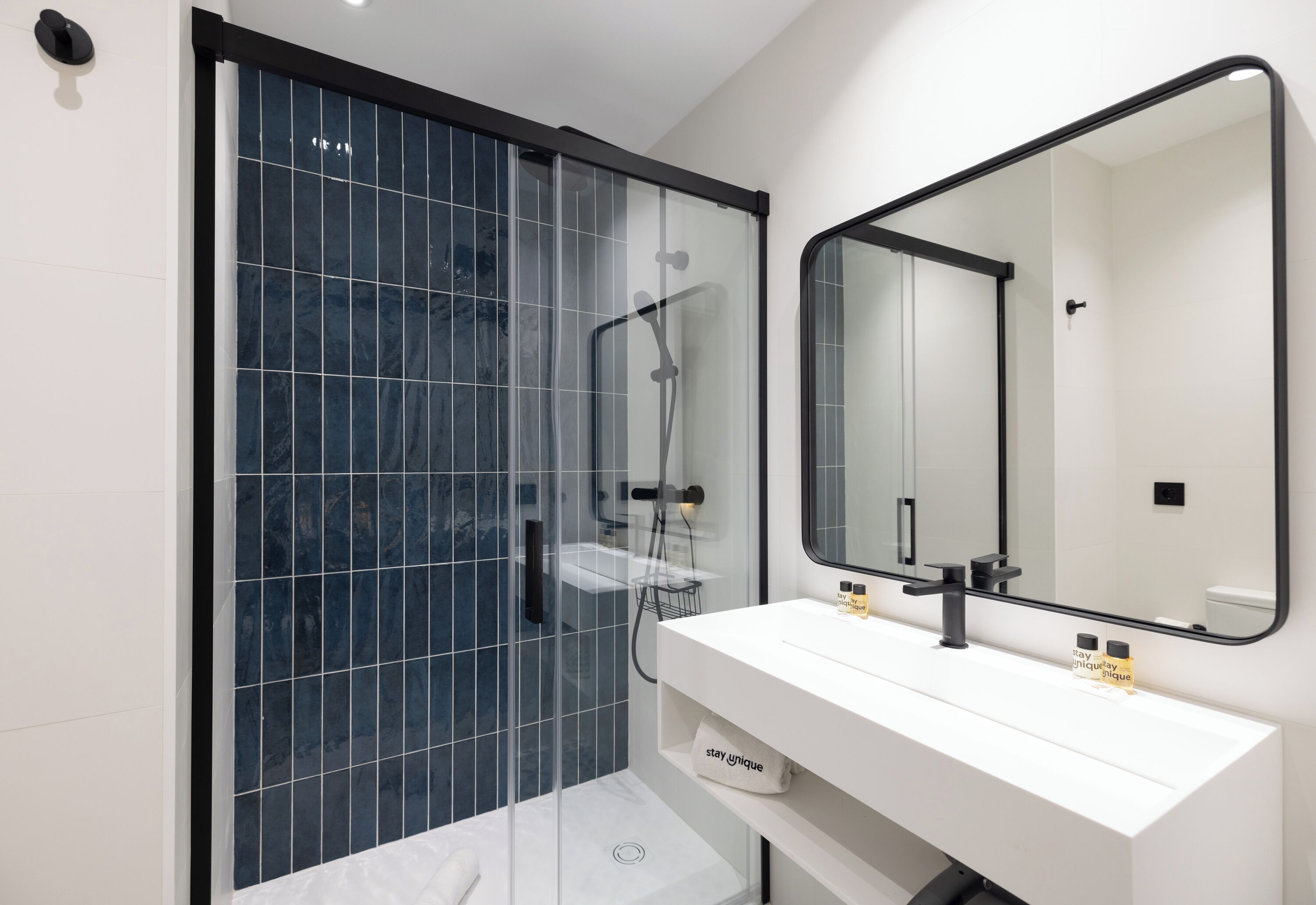 A modern bathroom with a glass-enclosed shower, a white vanity, and a large mirror.