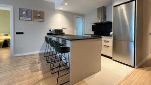 A modern kitchen with a central island, stainless steel appliances, and bar stools. - Stay U-nique Apartment Muntaner (Barcelona)