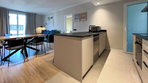 A modern kitchen with a central island, a dining area with a table and chairs, and a kitchenette with a microwave. - Stay U-nique Apartment Muntaner (Barcelona)