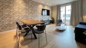 A modern living room with a brick wall, a wooden dining table, and a black sofa. - Stay U-nique Apartment Muntaner (Barcelona)