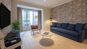 A living room with a sofa, a coffee table, a TV, a plant, and a brick wall. - Stay U-nique Apartment Muntaner (Barcelona)