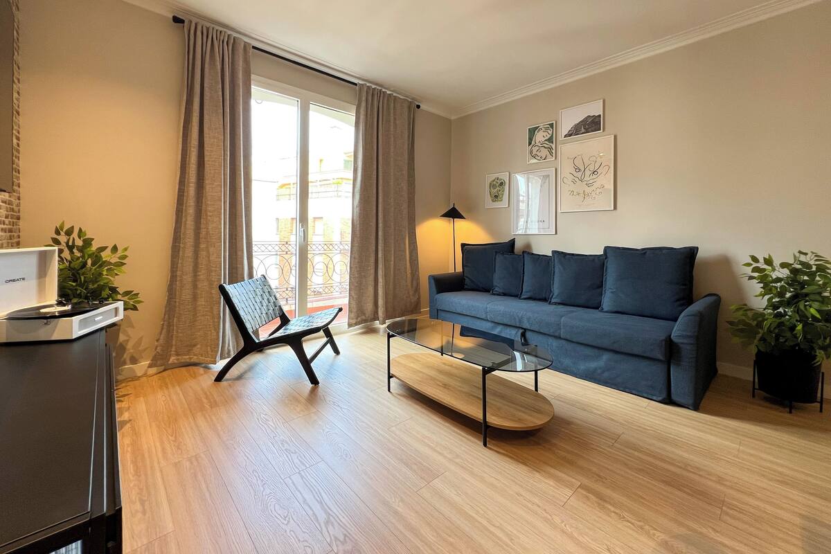 Un salón moderno con un sofá azul, una mesa de centro de madera, una silla negra y un tocadiscos.