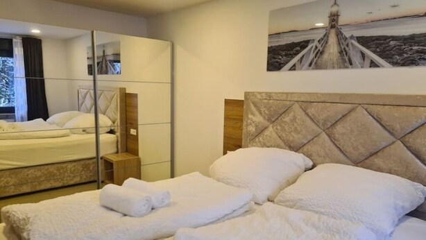 Ein Hotelzimmer mit einem großen Bett, einem Spiegel und einem Gemälde eines Leuchtturms.