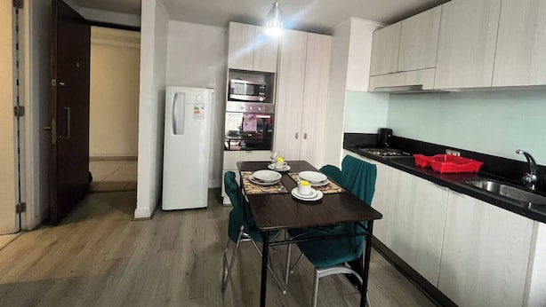 A compact kitchen with a dining area, featuring a refrigerator, microwave, oven, and a sink.