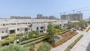 Un quartier résidentiel avec des immeubles d’appartements modernes, une route bien entretenue et, au loin, des grues de construction.