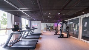 A gym with treadmills, weight machines, and a mirrored wall. - Dubai Hills Stunning 1 bed for 4 People (Dubai)