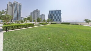 A well-maintained grassy area with modern buildings in the background. - Dubai Hills Stunning 1 bed for 4 People (Dubai)