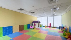 Ein Spielzimmer mit bunten Schaumstoffmatten, einem Spielhäuschen und Spielzeug.