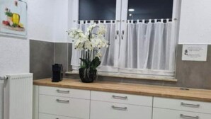 Een keuken met witte kastjes, een houten aanrecht en een raam met witte gordijnen.