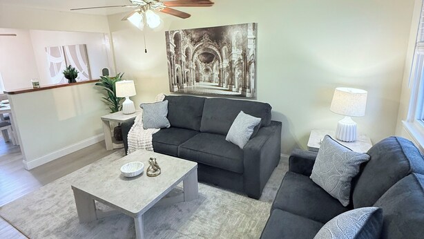 A living room with a grey sofa, a coffee table, and a ceiling fan.