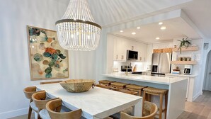 Une cuisine moderne avec des meubles blancs, un îlot central et un lustre.