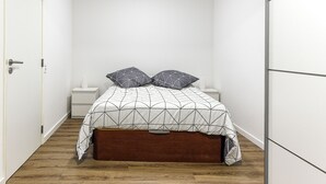 A narrow room with a bed, a nightstand, and a wardrobe.