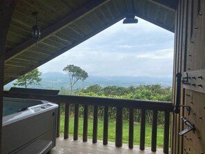 Een balkon met uitzicht op een weelderig landschap en bergen.