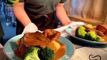 A plate of food with roast beef, Yorkshire pudding, and gravy, served on a blue plate.
