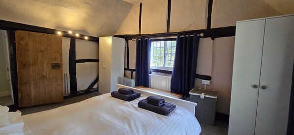 Un dormitorio con una cama grande, un armario, un radiador y una ventana con cortinas.