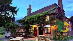 A traditional pub with a brick exterior, ivy-covered walls, and a sign reading "George & Dragon Pub". - The George & Dragon Pub - The Apartment (Horsham)