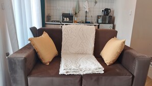 A brown leather sofa with a white throw blanket and two beige pillows.
