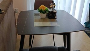A dining area with a table, chairs, a potted plant, and a bottle of olive oil.