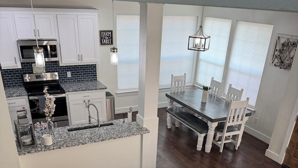 Cocina moderna con encimeras de granito, electrodomésticos de acero inoxidable y un letrero rústico.