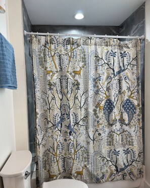 A bathroom with a shower curtain featuring a nature-themed pattern, a toilet, and a towel rack. - Fabulous 4-bedroom house in charming Pottsboro near Lake and Casino (Pottsboro)