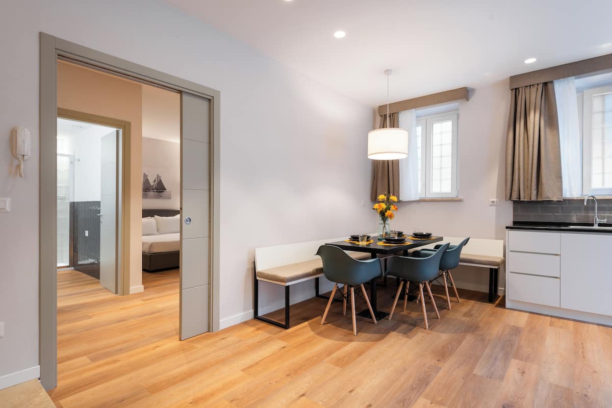 Una cocina moderna con comedor, piso de madera y vista al salón.