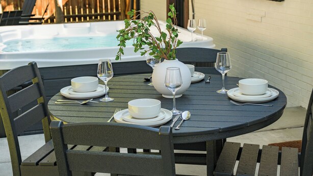 A round table set for four with white plates, bowls, and wine glasses, and a potted plant in the center. - Freshly remodeled home in Westminster. HotTub, Movie Theater, Pool Table, Arcade (Westminster)