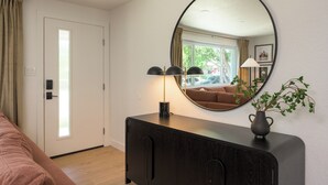 A room with a large mirror, a dark wooden cabinet, a potted plant, and a window with curtains. - Freshly remodeled home in Westminster. HotTub, Movie Theater, Pool Table, Arcade (Westminster)