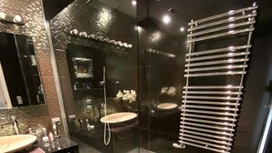 Une salle de bain moderne avec une douche à parois de verre, un meuble-lavabo noir avec un miroir et un lavabo blanc.