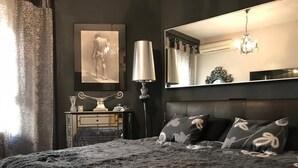 Une chambre à coucher avec un grand lit, une commode, un miroir et un lustre.