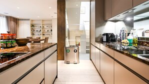 A modern kitchen with a central island, stainless steel appliances, and a trash bin. - Luxe 3BR/4BA Home w/ Air Con Games 5min Selfridges (Greater London)