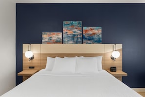 A hotel room with a bed, two bedside tables, a headboard with artwork, and wall-mounted reading lights. - La Quinta Inn & Suites By Wyndham Jackson (Jackson)