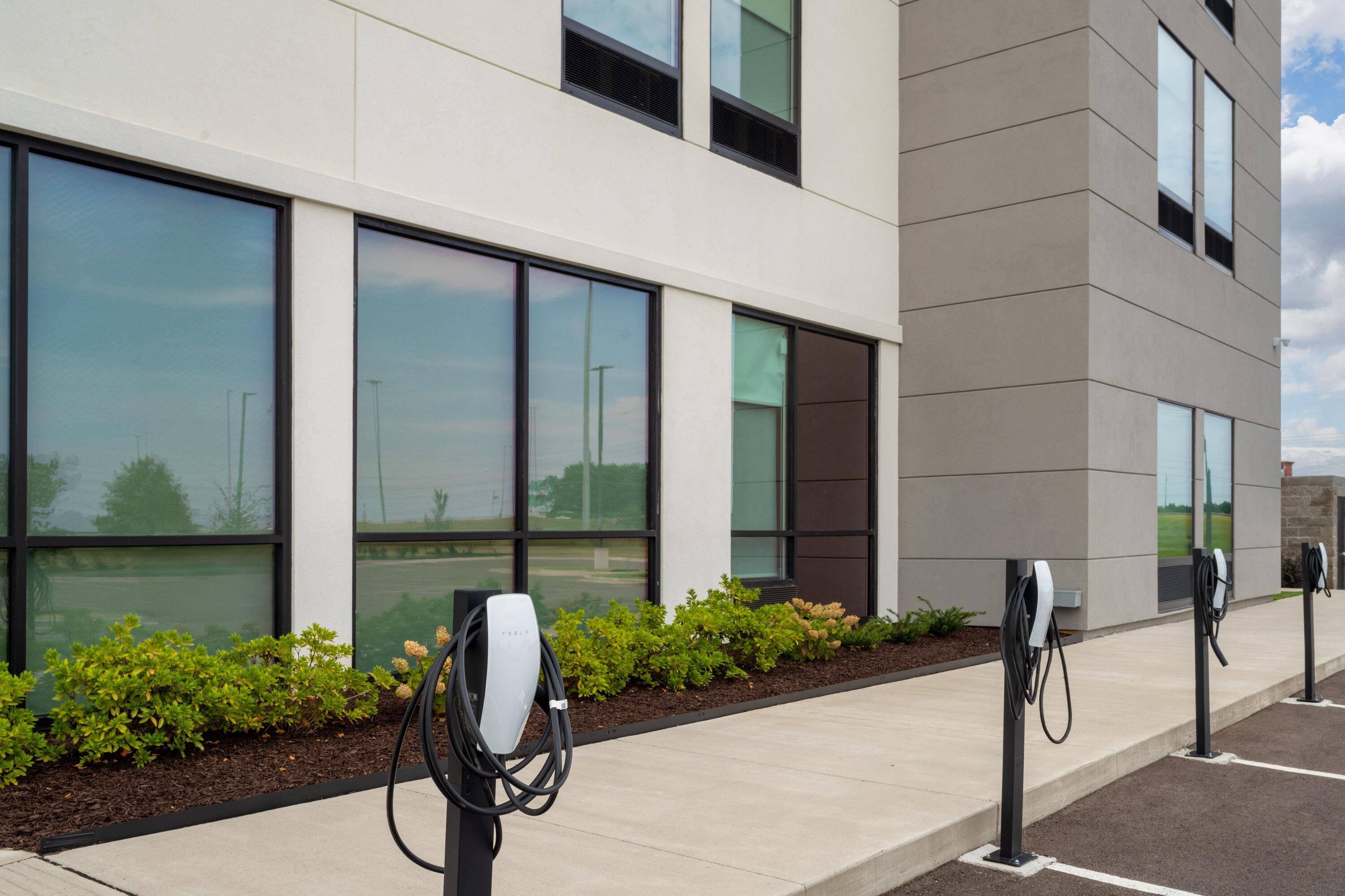 A modern building with large windows and a Tesla charging station.
