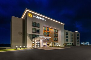 Un hotel de diseño moderno, con un llamativo logo de sol y el nombre 'LA QUINTA' en la fachada.