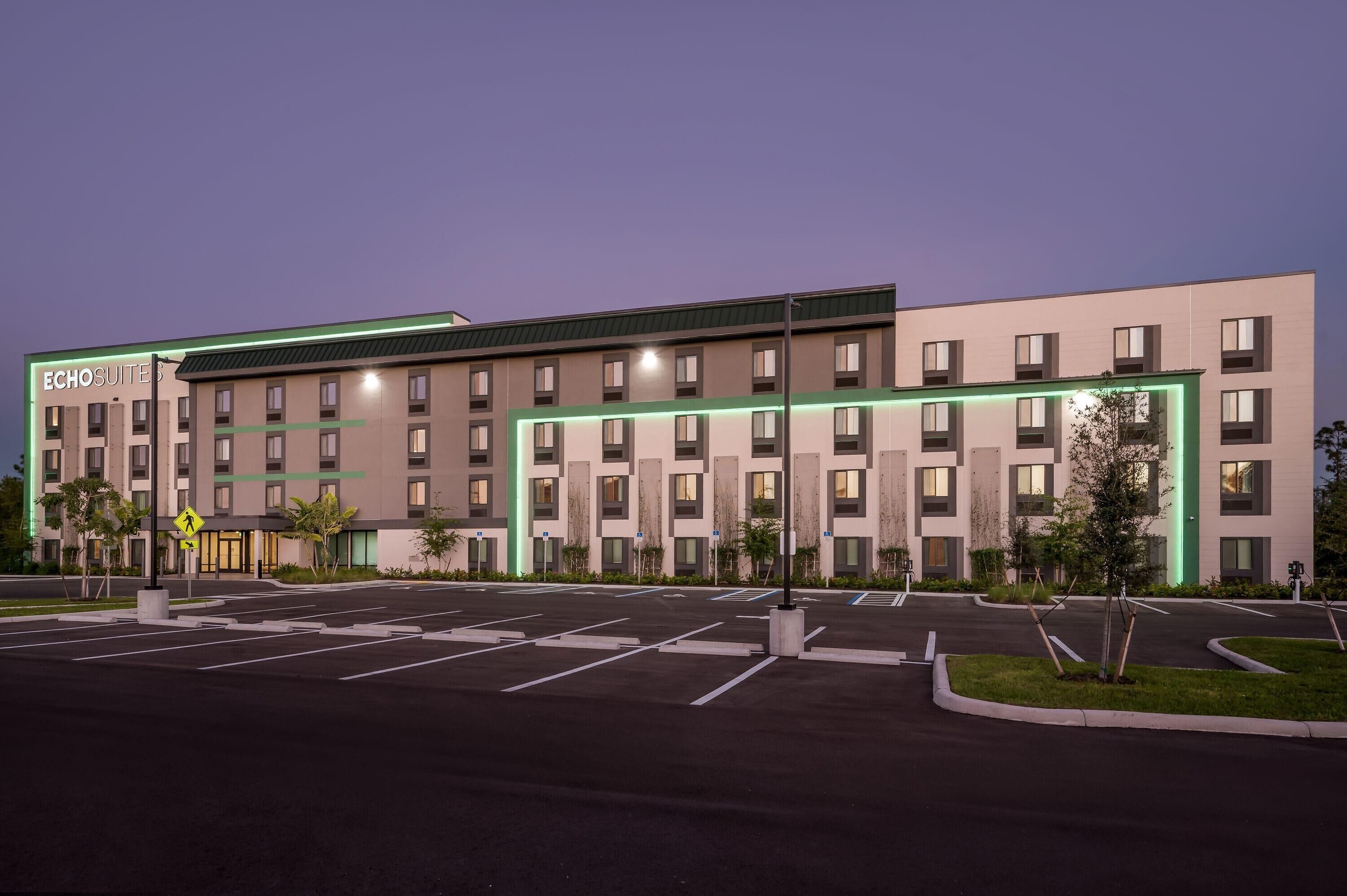 A modern hotel with a flat roof, multiple floors, and a parking lot.
