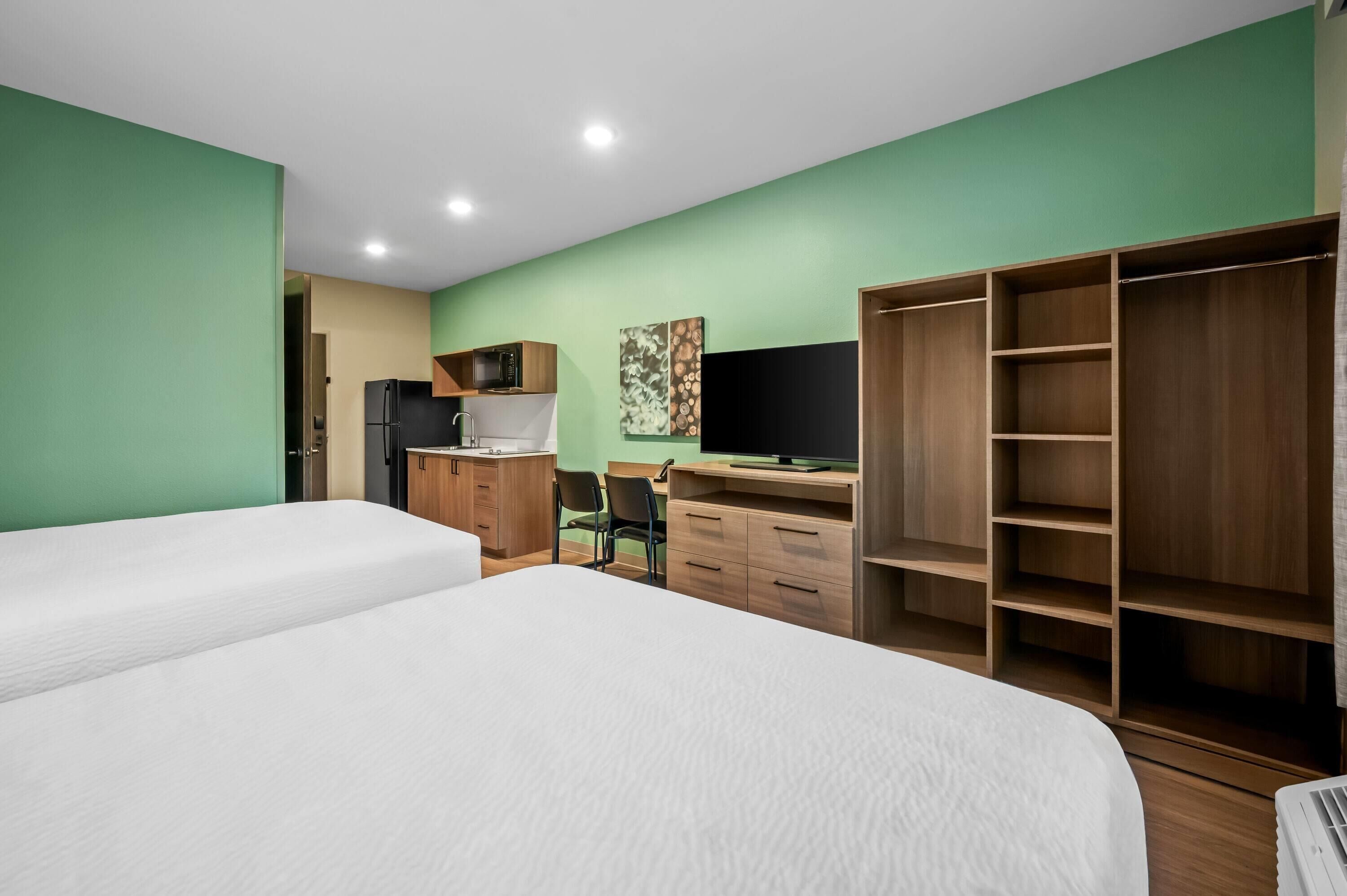 Quarto com cama, escrivaninha, cadeira, guarda-roupa e televisão.