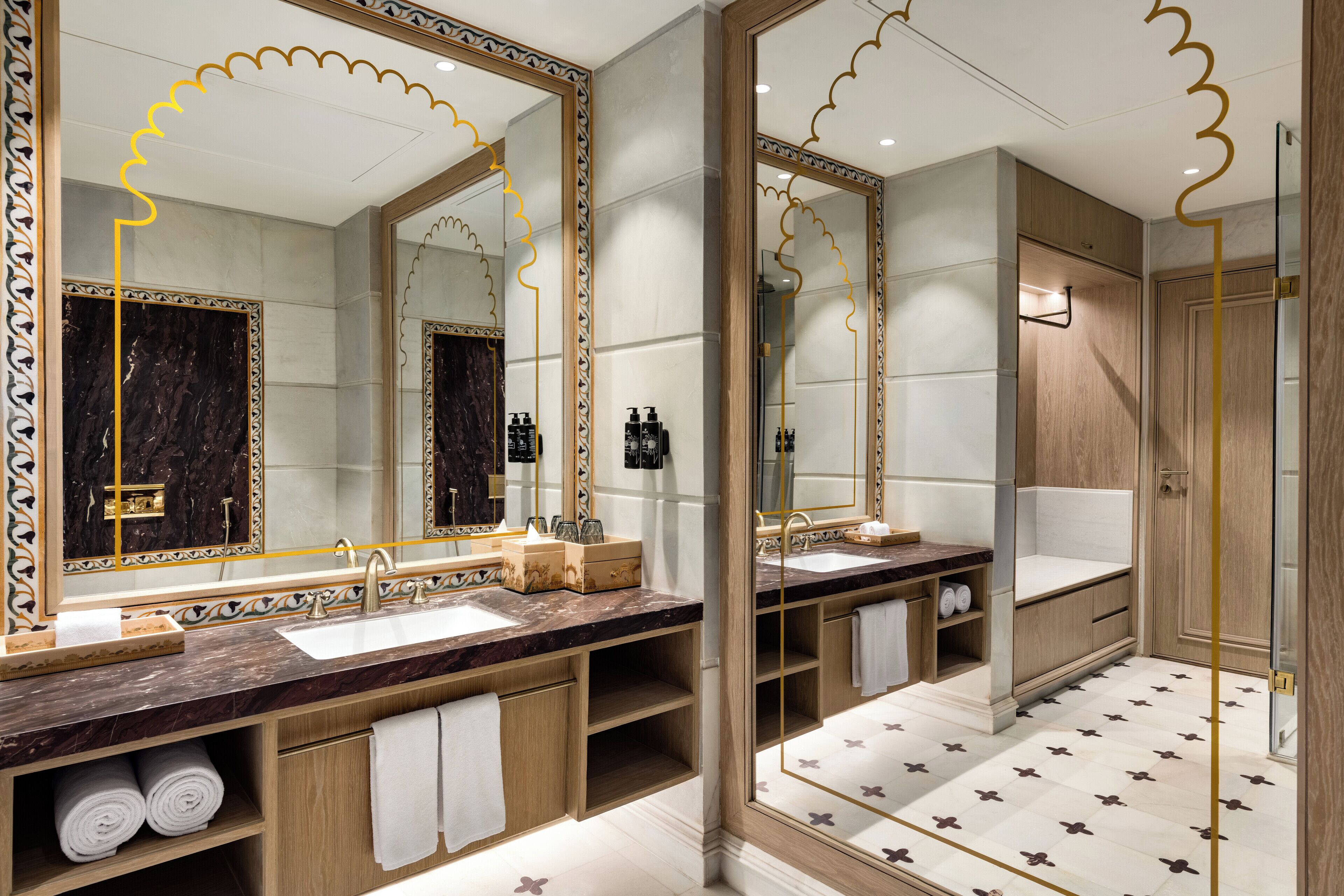 A luxurious bathroom with two sinks, marble countertops, and large mirrors.