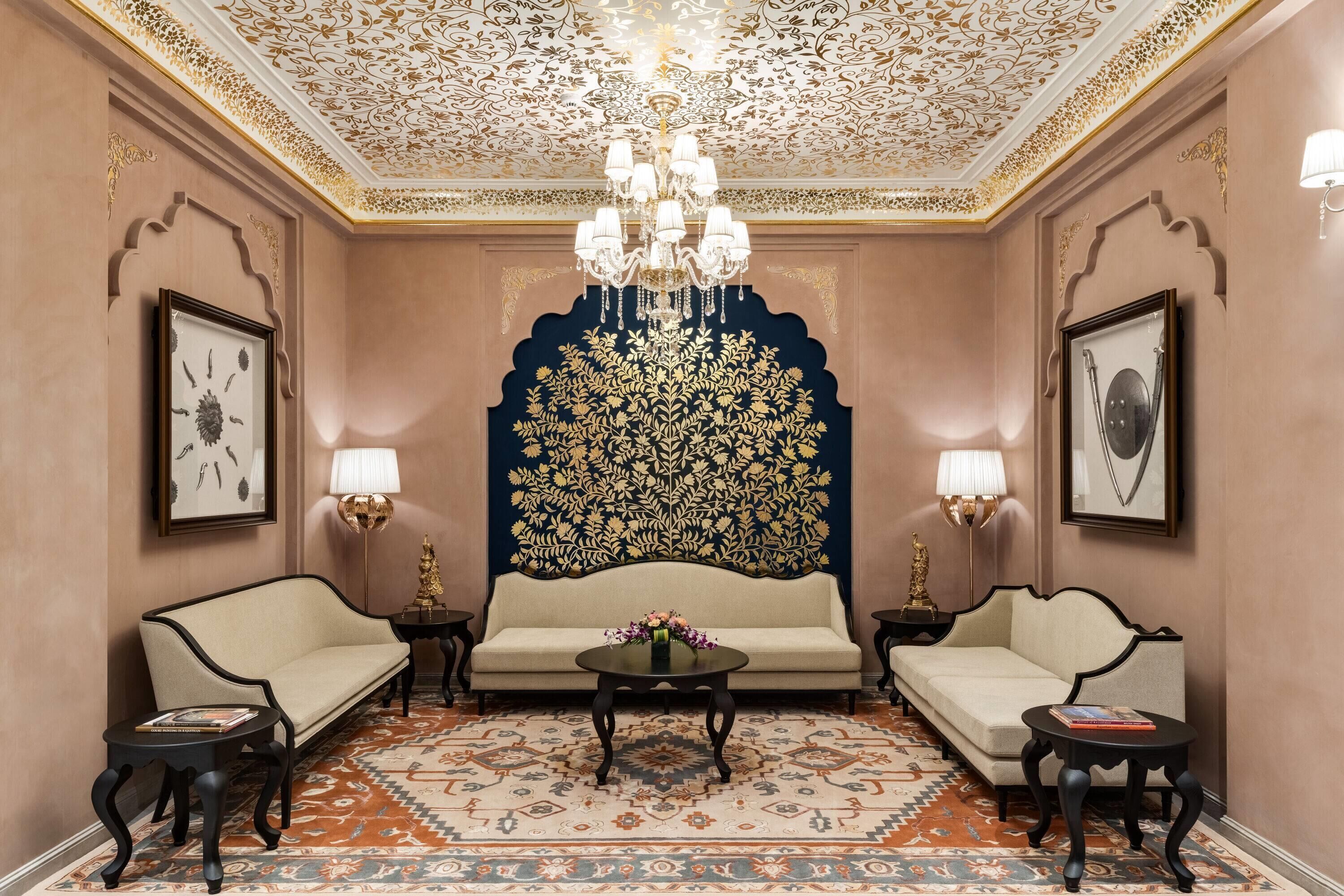 Um quarto com sofá, duas poltronas, um candelabro e tapete estampado.