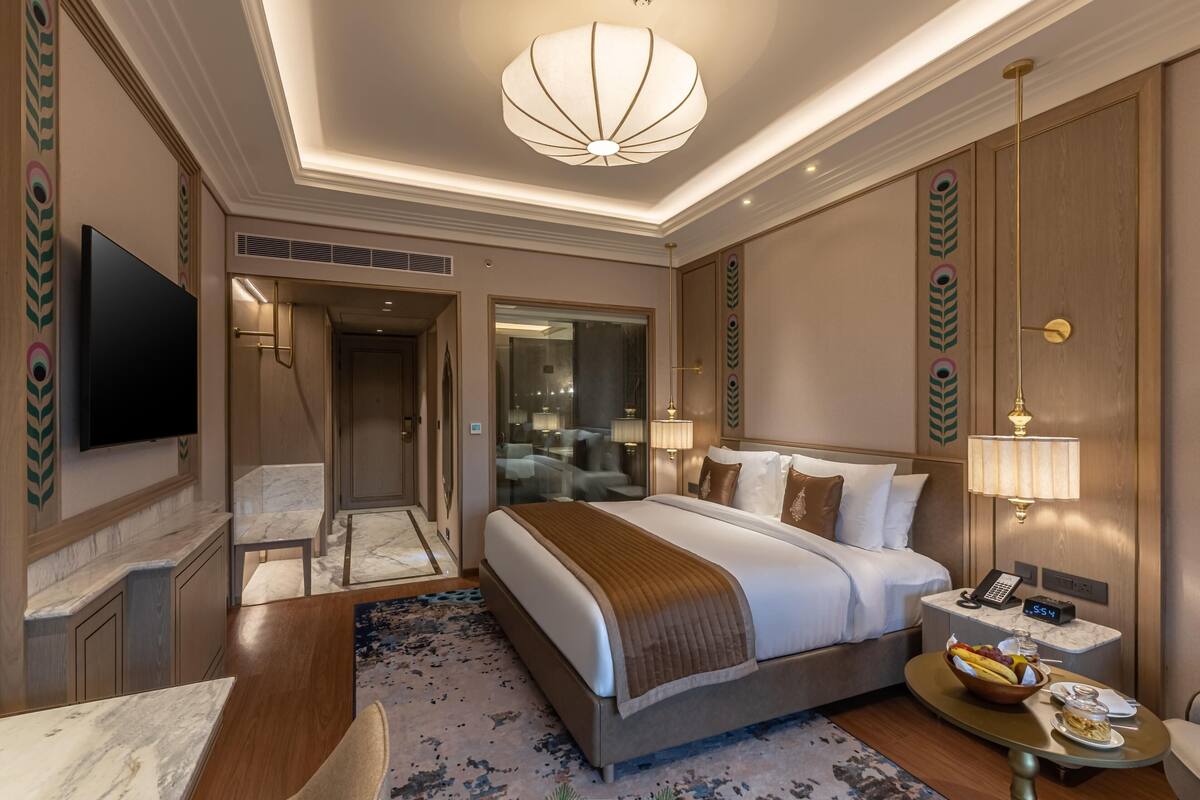 Ein Hotelzimmer mit einem großen Bett, Nachttisch, Lampe und einem Flachbildfernseher.