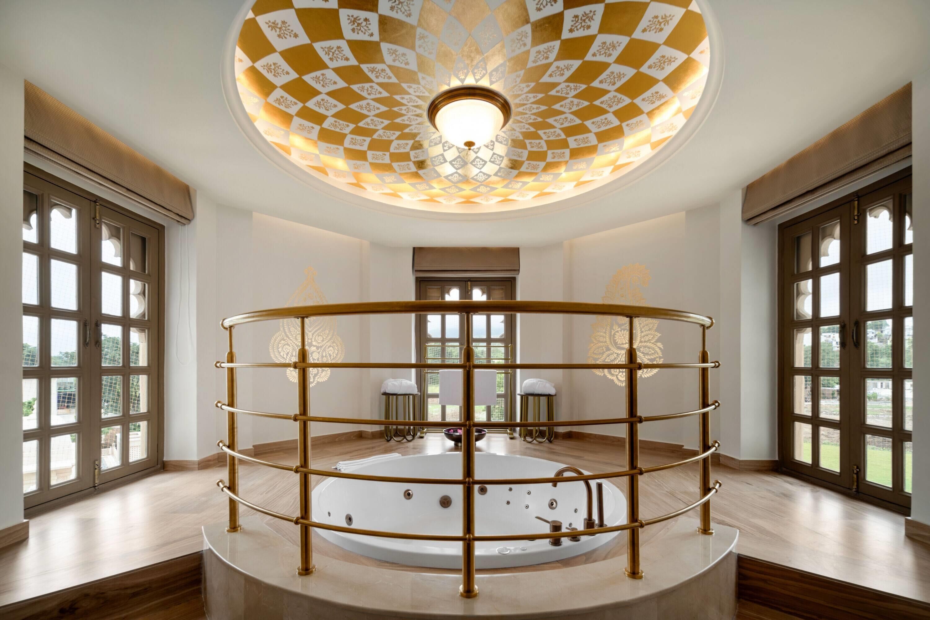 Un cuarto de spa con una bañera circular grande, un techo decorativo y ventanas amplias.