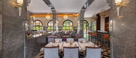 A restaurant with marble walls, chandeliers, and a checkered floor.