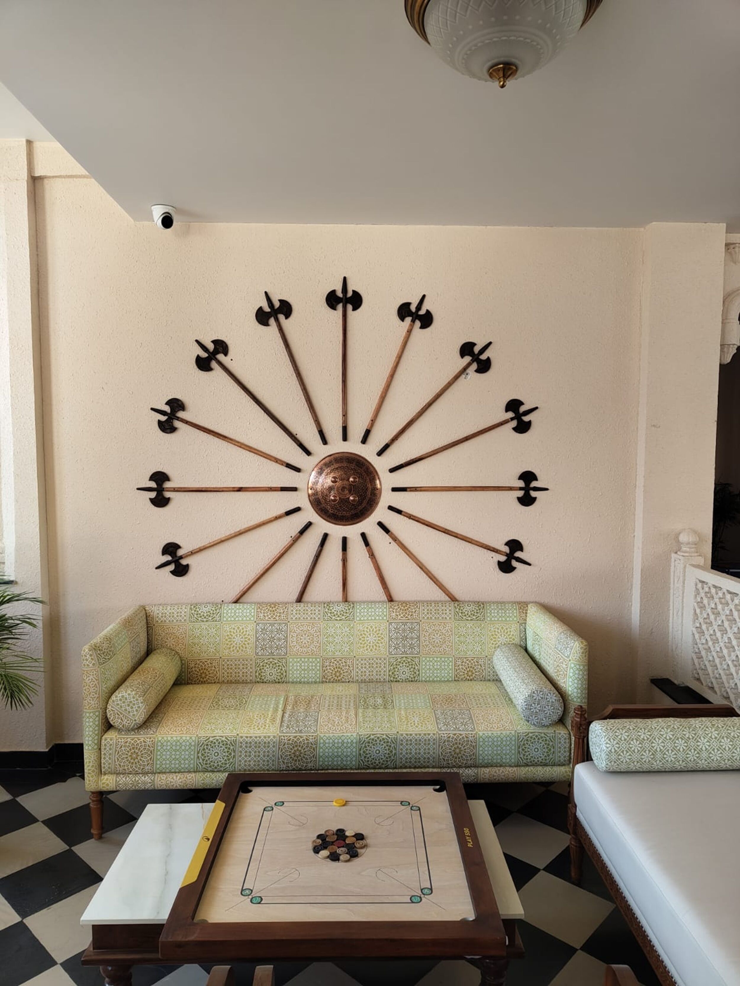 A room with a patterned sofa, a wooden coffee table with a board game, and a wall-mounted decorative piece.