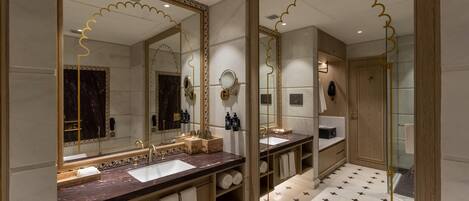Een badkamer met twee wastafels, grote spiegels en een douchehoek.