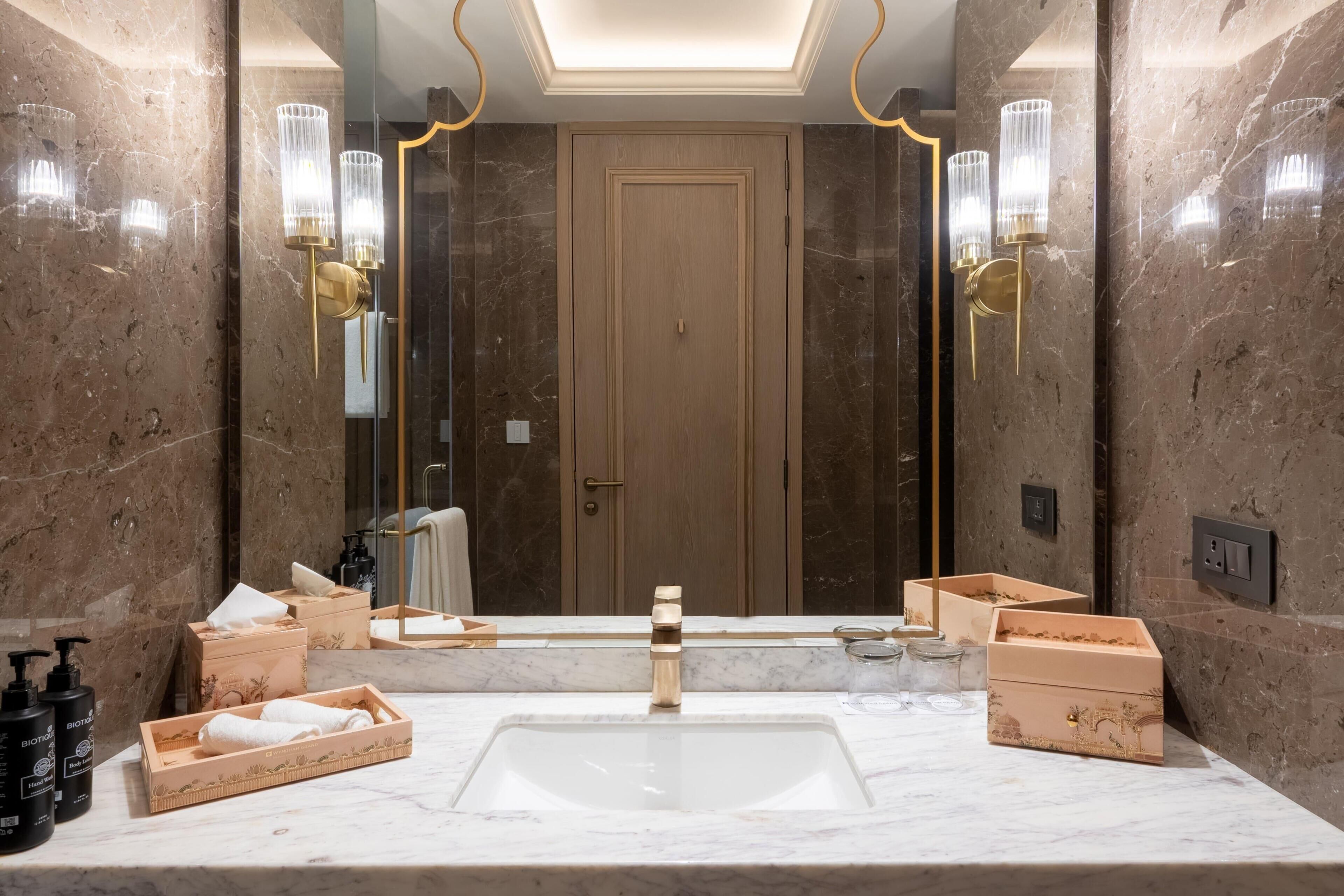 A bathroom with a marble sink, gold fixtures, and a large mirror.