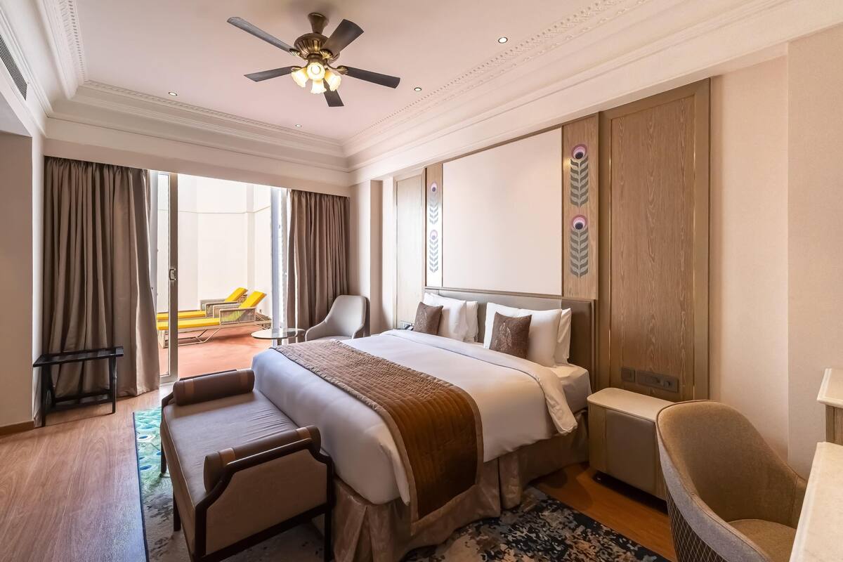 Ein Hotelzimmer mit einem großen Bett, einem Schreibtisch, einem Stuhl, einem Deckenventilator und Blick ins Freie.