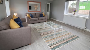 Un salon moderne avec un canapé gris, une table basse et un tapis à motifs.