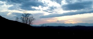 A mountainous landscape with a silhouette of a tree and distant mountains under a cloudy sky. - Heavenly Sunrise (Sevierville)