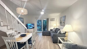 Un salon moderne comprenant un coin repas, un canapé, un téléviseur et un escalier.