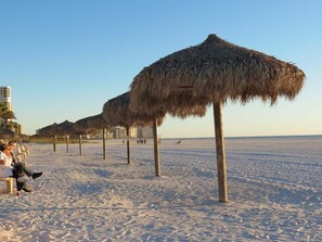 A beach with thatched umbrellas and a sandy shore.
