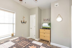 A bedroom with a bed, a dresser, a television, a door, and a window with blinds. - Mountain View Condo 1306 (Pigeon Forge)